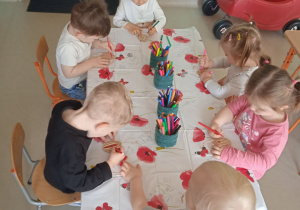 Dzieci z Klubu Dziecięcego "Niedźwiadek" podczas kolorowania drewnianych pisanek.