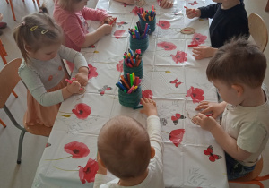 Dzieci z Klubu Dziecięcego "Niedźwiadek" podczas kolorowania drewnianych pisanek.