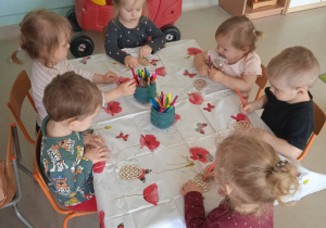 Dzieci z Klubu Dziecięcego "Niedźwiadek" podczas kolorowania drewnianych pisanek.