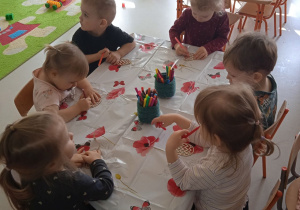 Dzieci z Klubu Dziecięcego "Niedźwiadek" podczas kolorowania drewnianych pisanek.