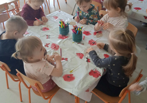 Dzieci z Klubu Dziecięcego "Niedźwiadek" podczas kolorowania drewnianych pisanek.