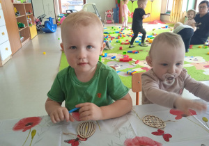 Dzieci z Klubu Dziecięcego "Niedźwiadek" podczas kolorowania drewnianych pisanek.