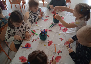 Dzieci z Klubu Dziecięcego "Niedźwiadek" podczas kolorowania drewnianych pisanek.