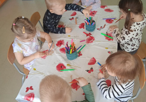 Dzieci z Klubu Dziecięcego "Niedźwiadek" podczas kolorowania drewnianych pisanek.