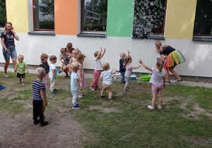 Maluszki łapią banieczki mydlane.