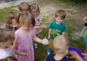 Nikusia trzyma magiczną bańkę mydlaną z zawartym w niej dymkiem. Wokół są obserwujące z zaciekawieniem dzieci.