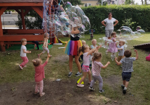 Pani tworzy ogromne banieczki dla wszystkich dzieci. Niedźwiadki z radością próbują je łapać.