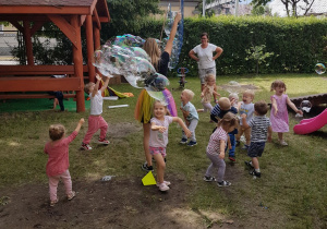 Pani tworzy ogromne banieczki dla wszystkich dzieci. Niedźwiadki z radością próbują je łapać.