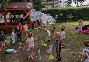 Pani tworzy ogromne banieczki dla wszystkich dzieci. Niedźwiadki z radością próbują je łapać.