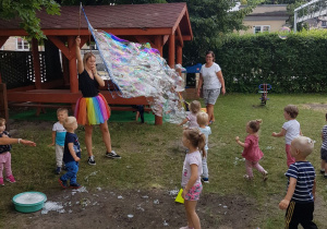 Pani tworzy ogromne banieczki dla wszystkich dzieci. Niedźwiadki z radością próbują je łapać.