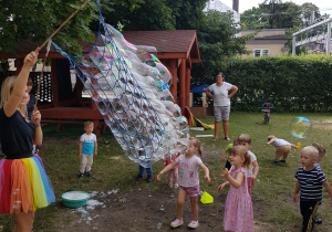 Pani tworzy ogromne banieczki dla wszystkich dzieci. Niedźwiadki z radością próbują je łapać.