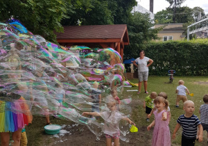 Pani tworzy ogromne banieczki dla wszystkich dzieci. Niedźwiadki z radością próbują je łapać.