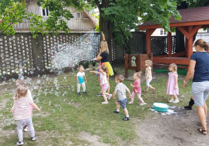 Pani tworzy ogromne banieczki dla wszystkich dzieci. Niedźwiadki z radością próbują je łapać.