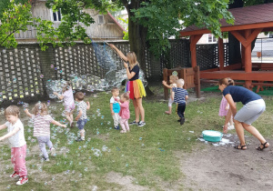 Pani tworzy ogromne banieczki dla wszystkich dzieci. Niedźwiadki z radością próbują je łapać.