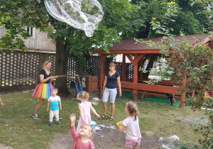 Pani tworzy ogromne banieczki dla wszystkich dzieci. Niedźwiadki z radością próbują je łapać.