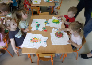 Dzieci z grupy Niedźwiadek malują farbami na koszulkach.